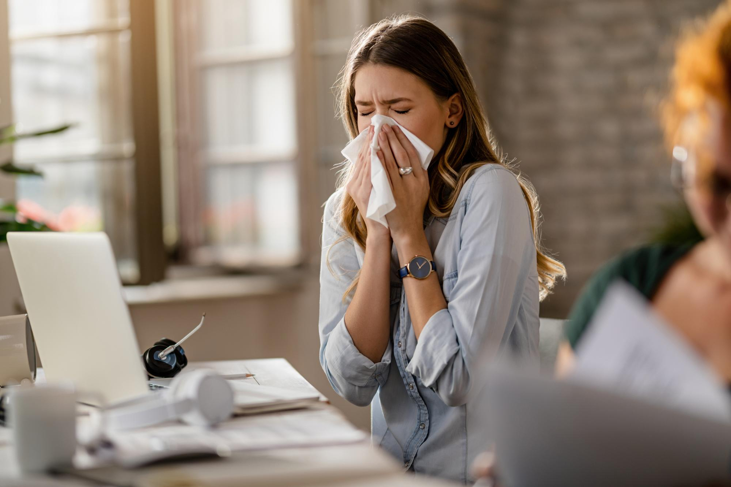 woman sneezing into tissue arnot health